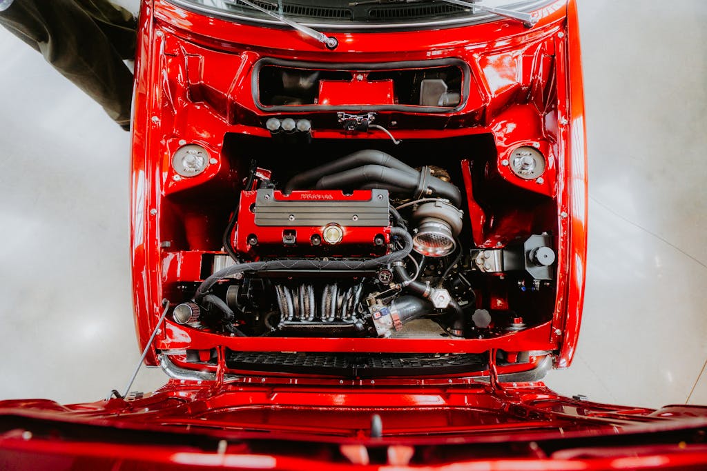 Top-down view of a car engine in a vividly red automobile, showcasing detailed components.